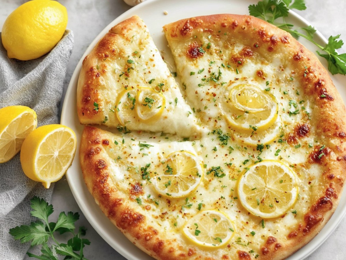 A lemon pizza in overhead view. Next to it are fresh ingredients.