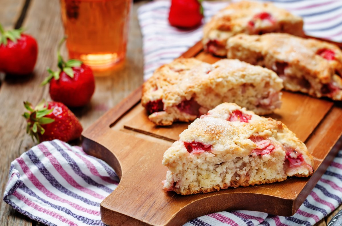 Strawberry buttermilk scones on a board, strawberries and striped kitchen towel.
