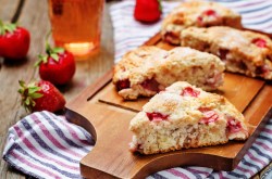 Strawberry buttermilk scones on a board, strawberries and striped kitchen towel.